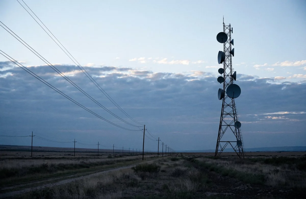 Funkturm mit Richtfunkantennen ueber einer weiten Landschaft in den USA